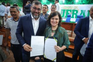 Imagem colorida mostra o governador do Amazonas Wilson Lima e a ministra da saúde Nísia Trindade segurando documento de acordo de compromisso