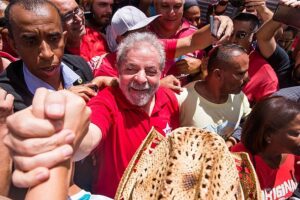 Imagem colorida mostra Lula sendo cumprimentado por populares