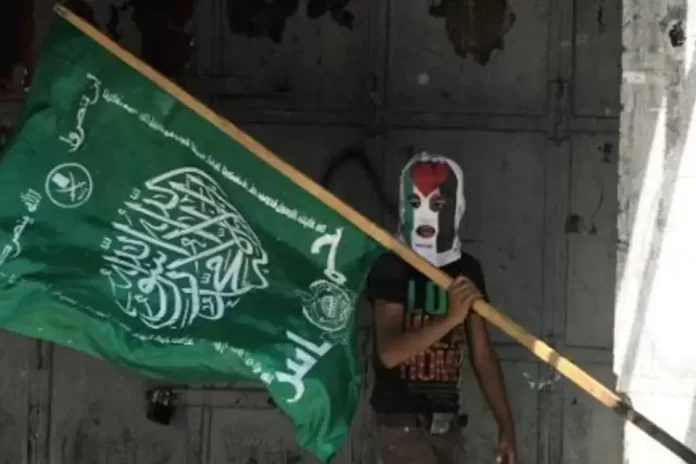 Imagem colorida mostra manifestante pró estado da Palestina e Hamas, segurando bandeira do grupo Hamas