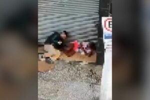 Homem se aproximando da vítima que estava deitada na calçada.